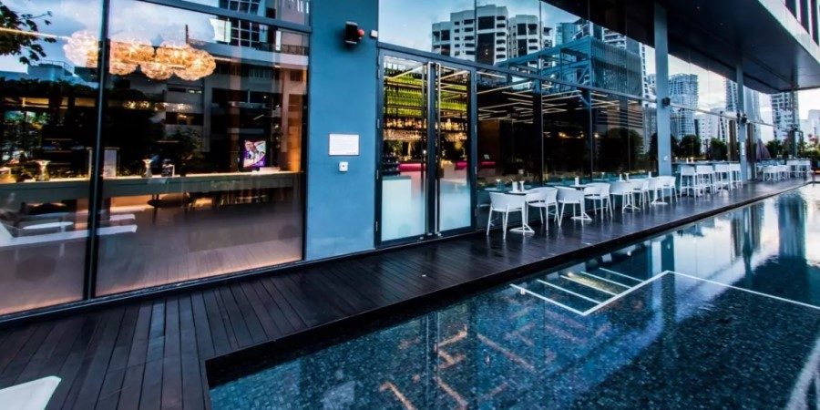 A serene pool area featuring glass walls and comfortable chairs for lounging.
